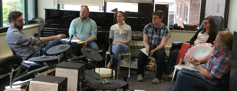 People sitting in a circle surrounded by instruments