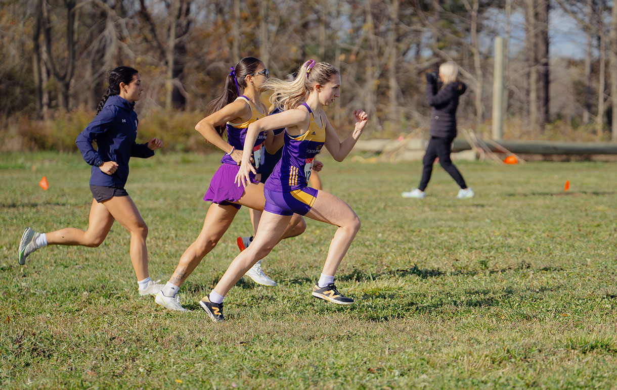 Mya Baxter cross-country running across a green field