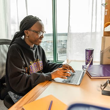 student on laptop in dorm