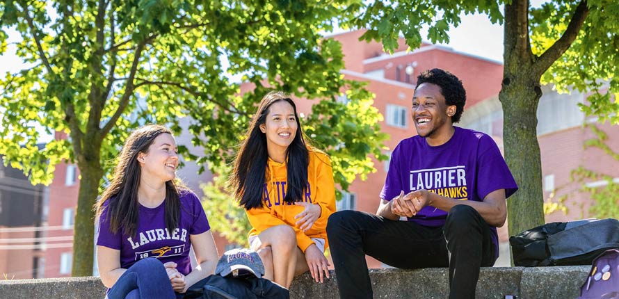 group of students sitting on the grass on Waterloo campus.